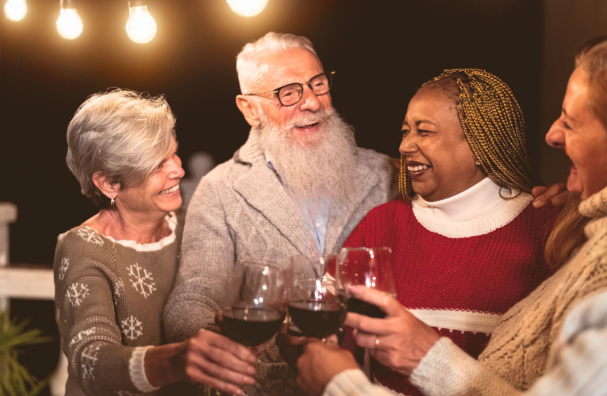 Buda Oaks | Group of seniors cheersing red wine outside surrounded by string lights