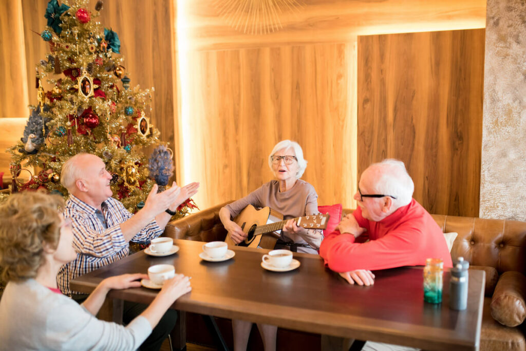 Buda Oaks | Group of happy seniors sitting around the Christmas tree playing music