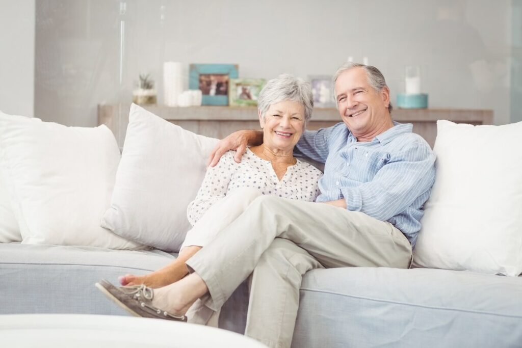 Buda Oaks | Senior couple sitting on their couch smiling